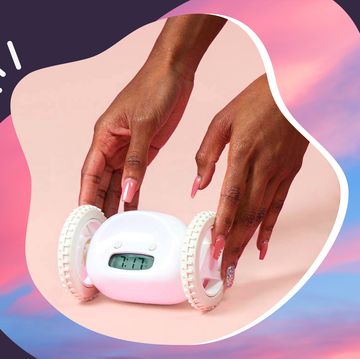 woman with pink nails holding clocky wheeled alarm clock with sunrise background
