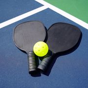 pickleball paddles and yellow ball on court